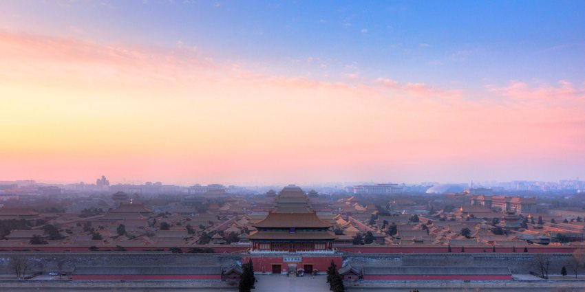 The halls and rooftops of the Forbidden City viewed from Jingshan beneath an evening sky.