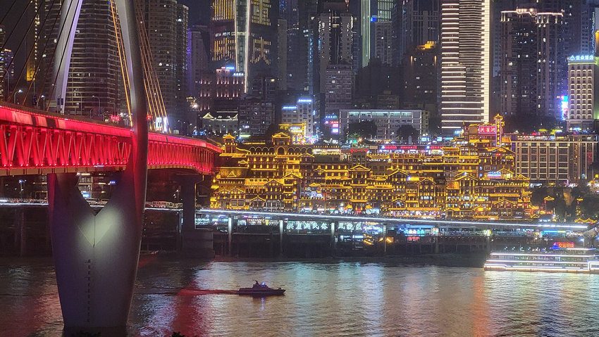 Illuminated Hongya Cave buildings and the red Qiansimen Bridge beside the Jialing River in Chongqing