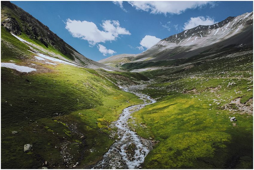 A stream winding through a green mountain valley