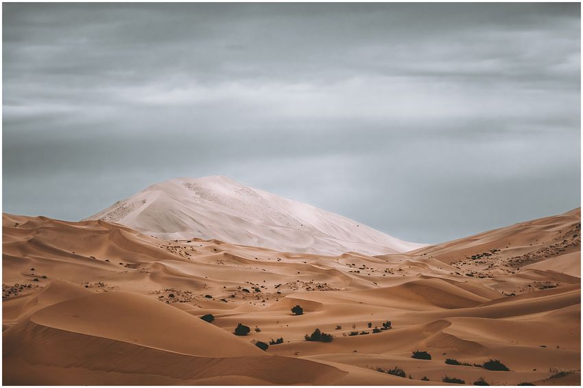 Layers of light and dark dunes beneath grey clouds