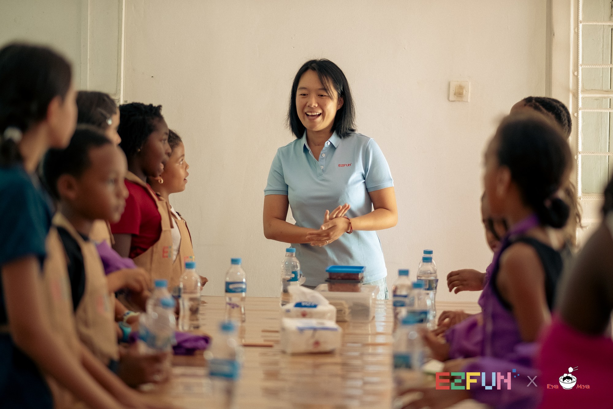 An instructor welcomes the children gathered around the workshop table.