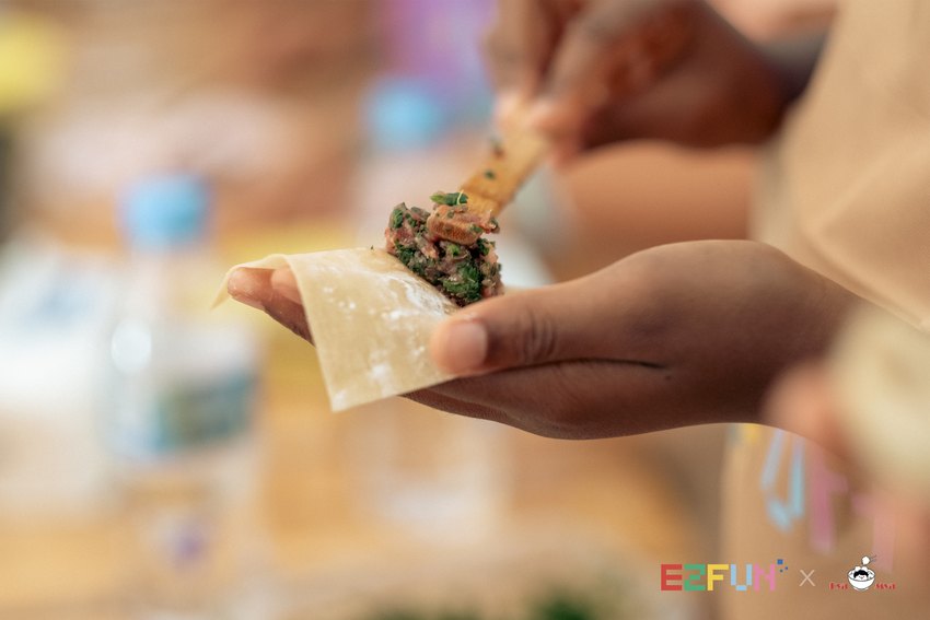 A spoonful of filling is placed onto a wonton wrapper held in one hand.