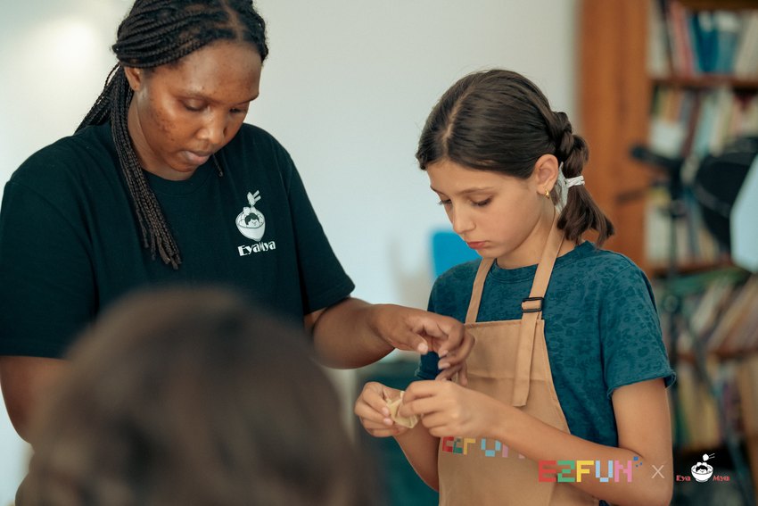 An adult guides a child through a step of making wontons.