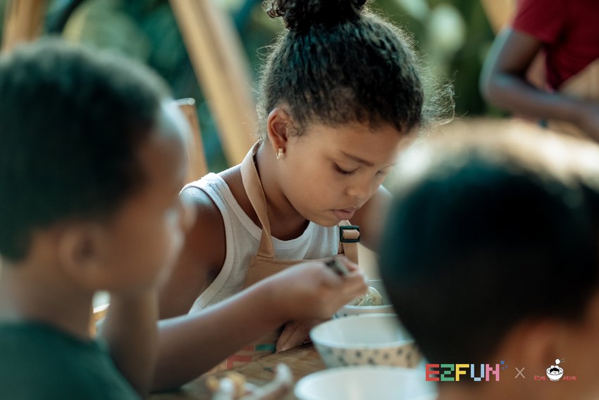 A child leans over a bowl to taste the food.