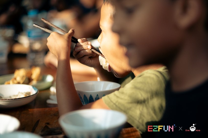 A child tastes a spoonful beside bowls on the table.