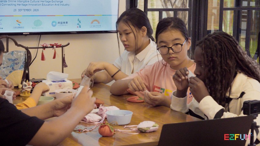 Participants make sachets around a table beneath the event screen