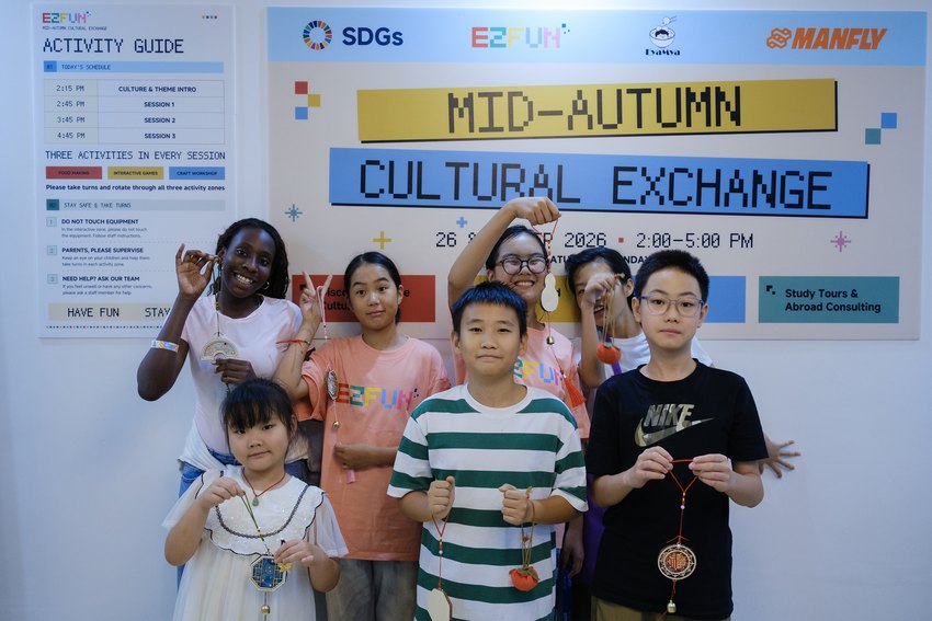 Children display their handmade Mid Autumn decorations in front of the event poster