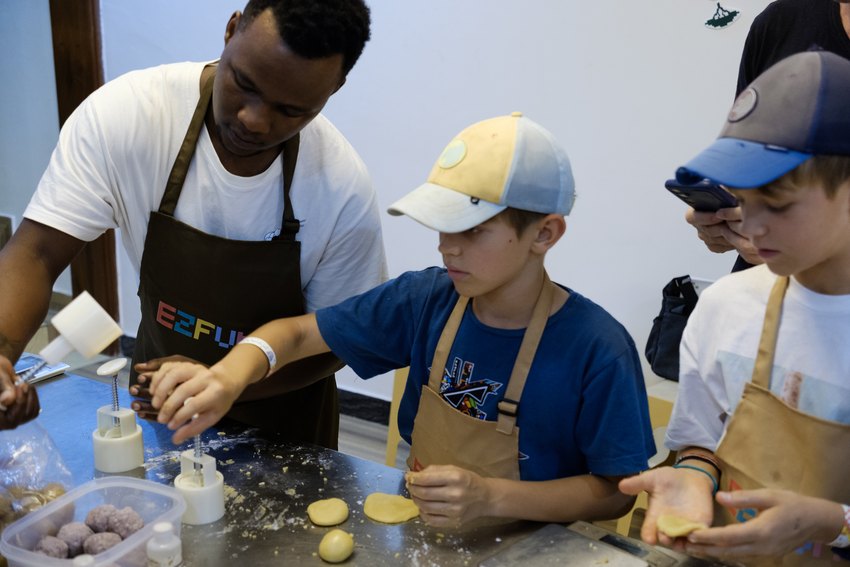 A facilitator guides children as they press mooncakes into moulds