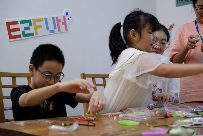 Children choose materials and make festive decorations at the craft table