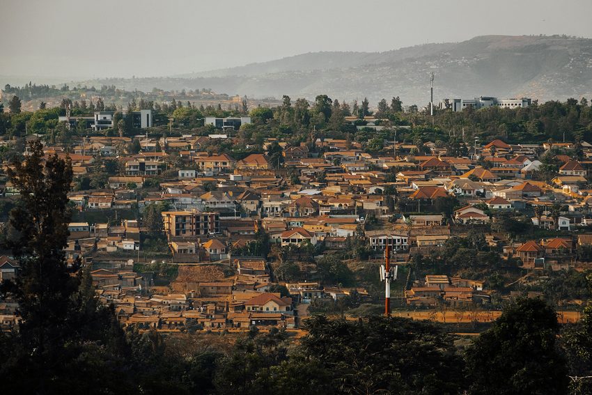 Dense rooftops spread across rolling terrain beneath hazy hills.