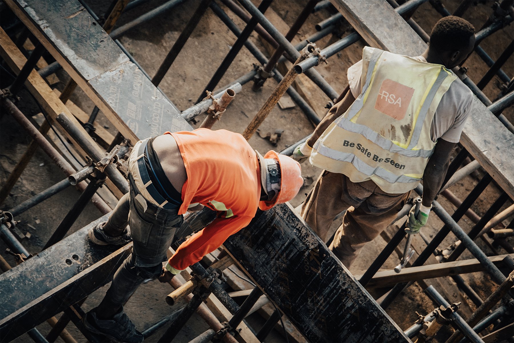 Workers use tools beside a timber structure.