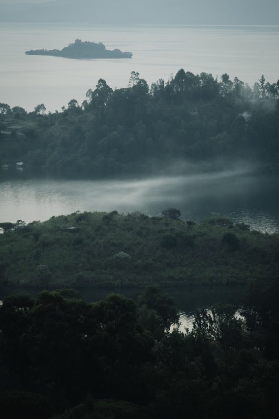 Wooded shores and distant islands sit beneath a pale layer of mist.