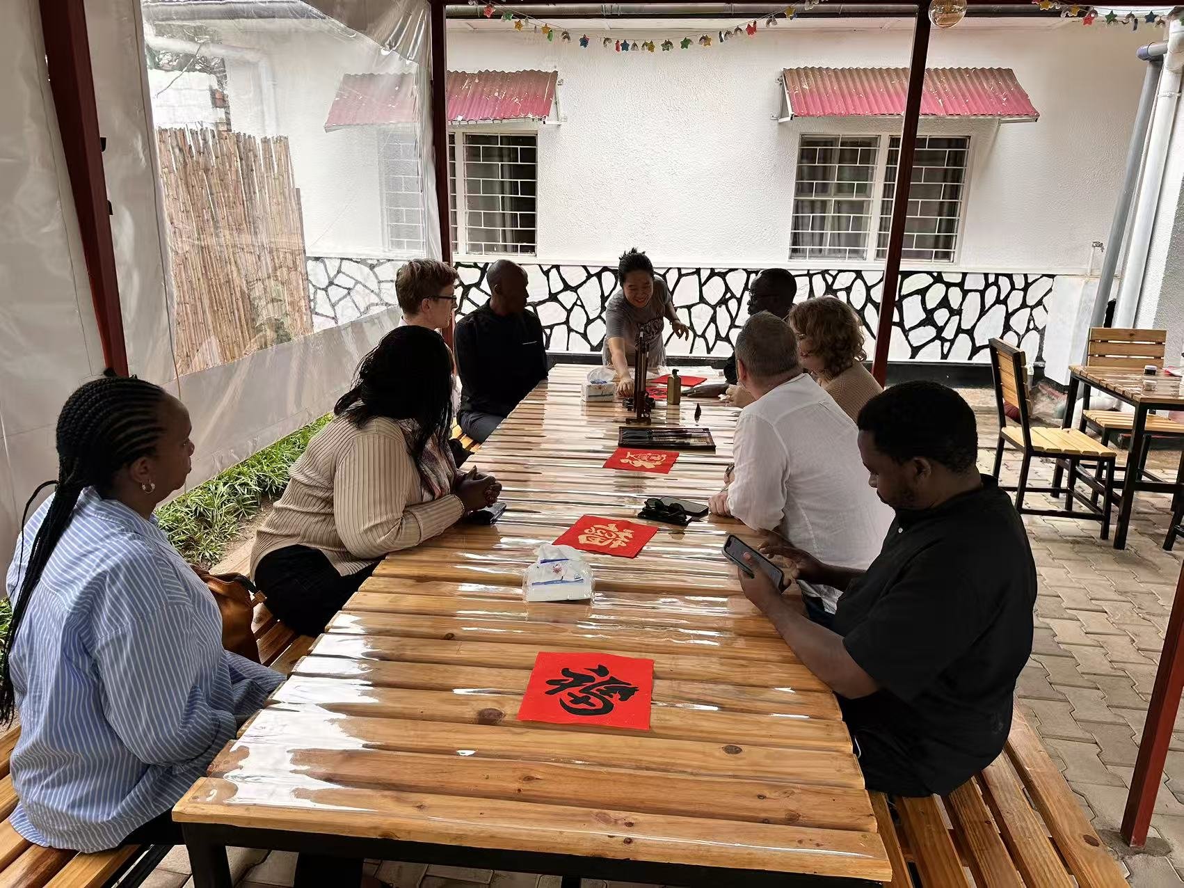 Participants sit along a long table laid with red paper.