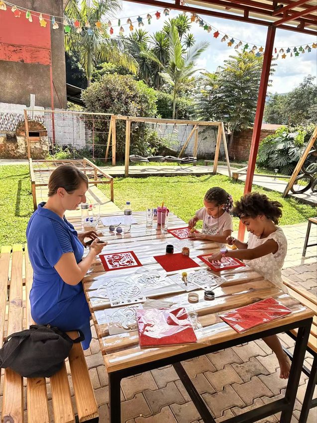 Participants work at a table with red paper beneath an open-sided shelter.