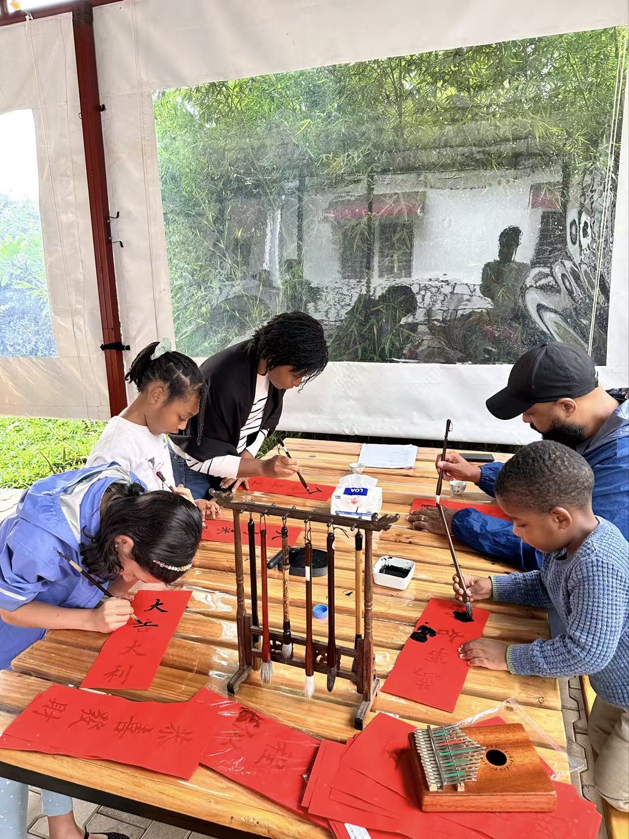 Participants lean over a long table to work with red paper and craft materials.