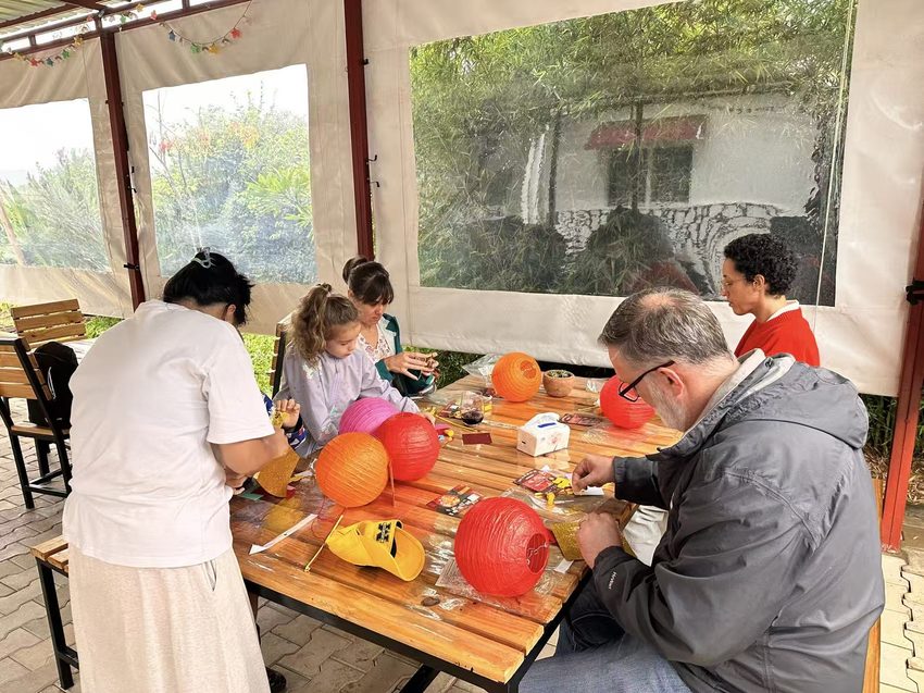 Adults and children work together with red lanterns and decorative materials.