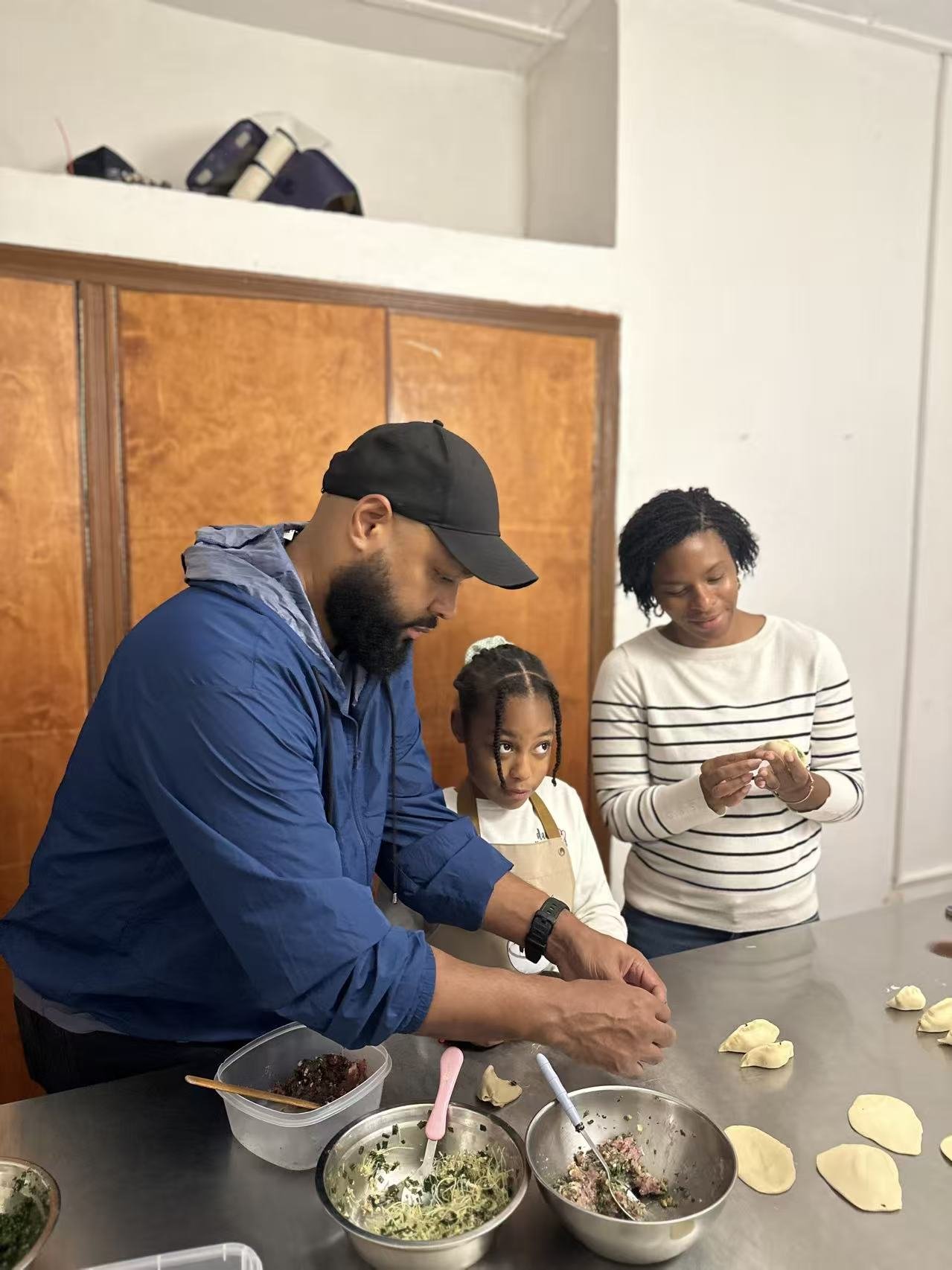 Adults and a child work with dough at a kitchen counter.