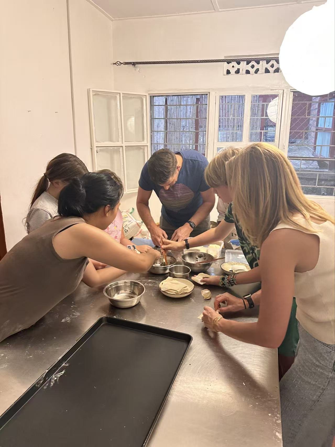 Participants lean together around ingredients in a bowl at the kitchen counter.